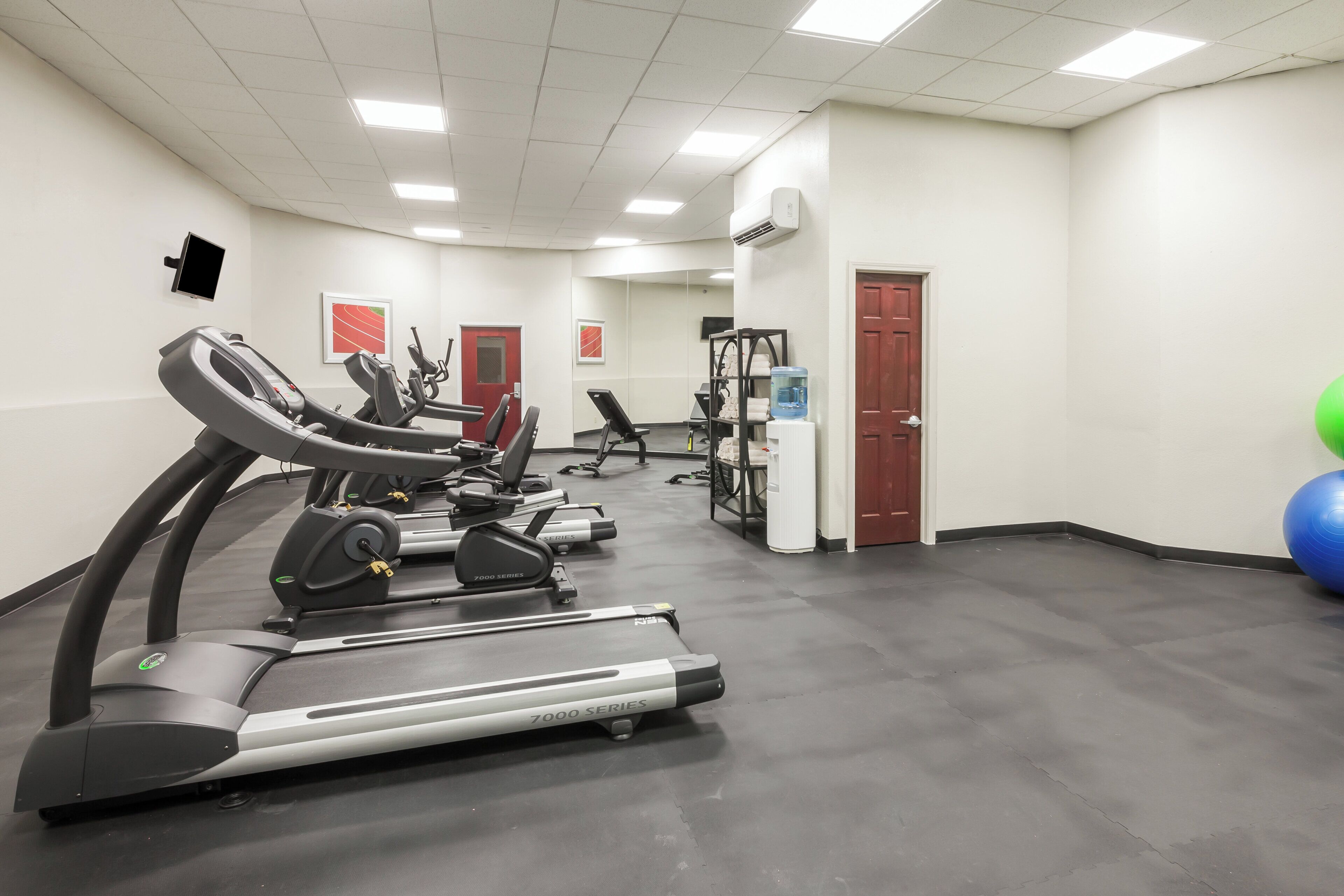 Un gimnasio con cintas de correr, bicicletas estáticas y máquinas de pesas.