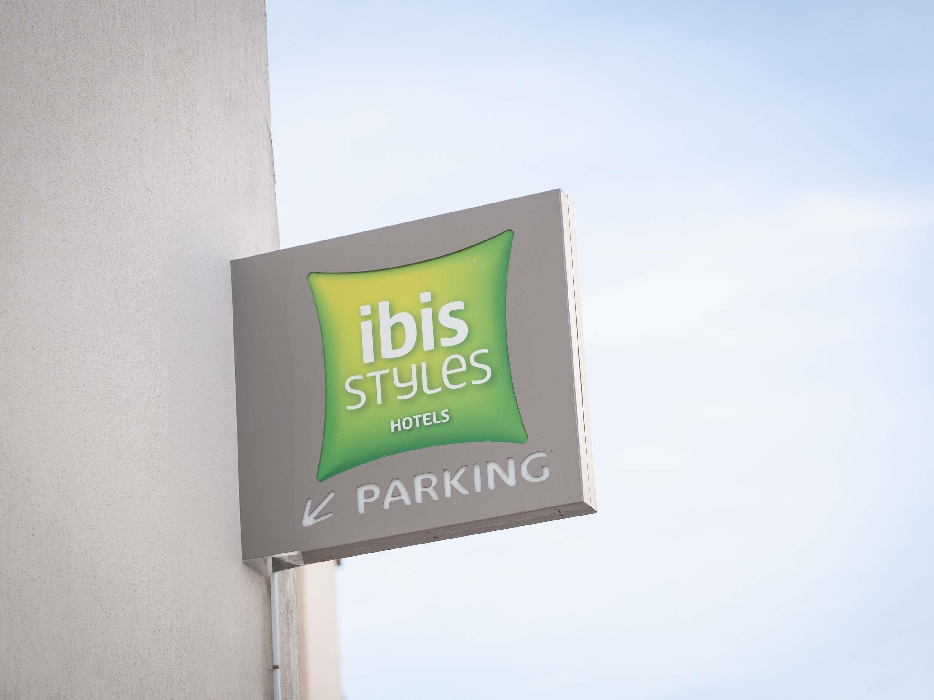 Señal de ibis Styles Hotels con indicaciones para estacionamiento.
