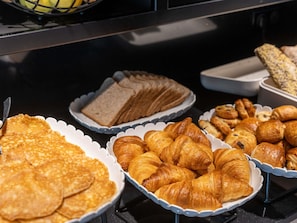 Une variété de produits de boulangerie, notamment des crêpes, des croissants et du pain, sont exposés.