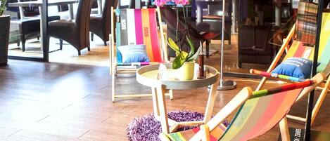 A modern lounge area with comfortable seating, including a colorful striped lounge chair and a small table with a potted plant.