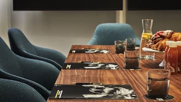 Une table de conférence avec des dossiers noirs, des stylos et des verres d’eau.