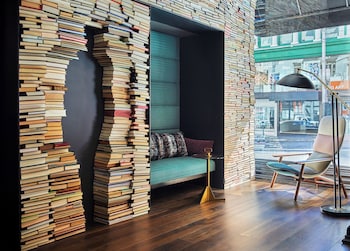 A modern lounge area with a long table, multiple chairs, and a television screen displaying a fire. at Hotel Emblem San Francisco