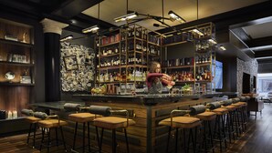 A bar area with a bartender, wooden shelves with bottles, and bar stools. - Hotel Emblem San Francisco (San Francisco)