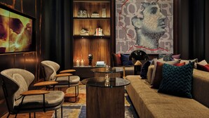 A modern living room with a sofa, armchairs, a glass coffee table, a bookshelf, and a large abstract painting. - Hotel Emblem San Francisco (San Francisco)