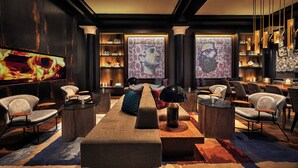 A modern lounge area with a long table, multiple chairs, and a television screen displaying a fire. - Hotel Emblem San Francisco (San Francisco)