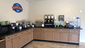 Un coin petit-déjeuner équipé d’une machine à café, d’un four à micro-ondes et d’une enseigne indiquant « Baymont Breakfast Corner ».