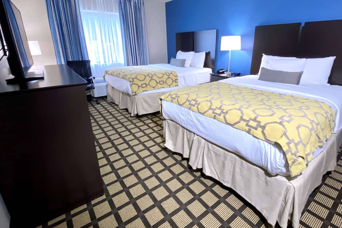 Ein Hotelzimmer mit zwei Betten, einem Schreibtisch und einem Stuhl.