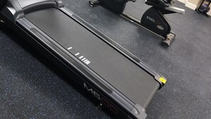 Une salle de sport équipée d’un tapis de course, d’un vélo elliptique et d’un vélo d’appartement.