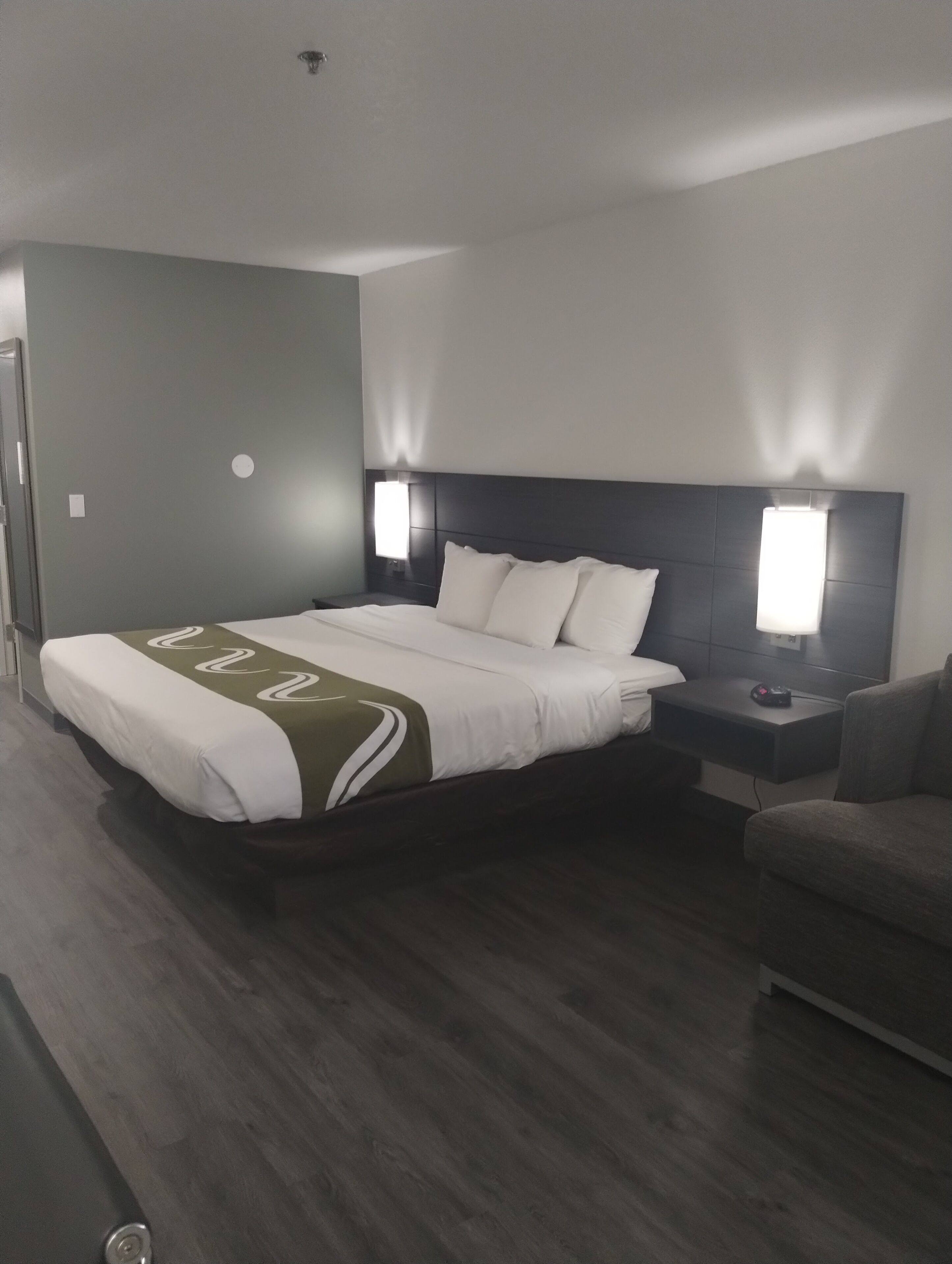 Una habitación de hotel moderna con una cama grande, dos mesitas de noche y un sofá.