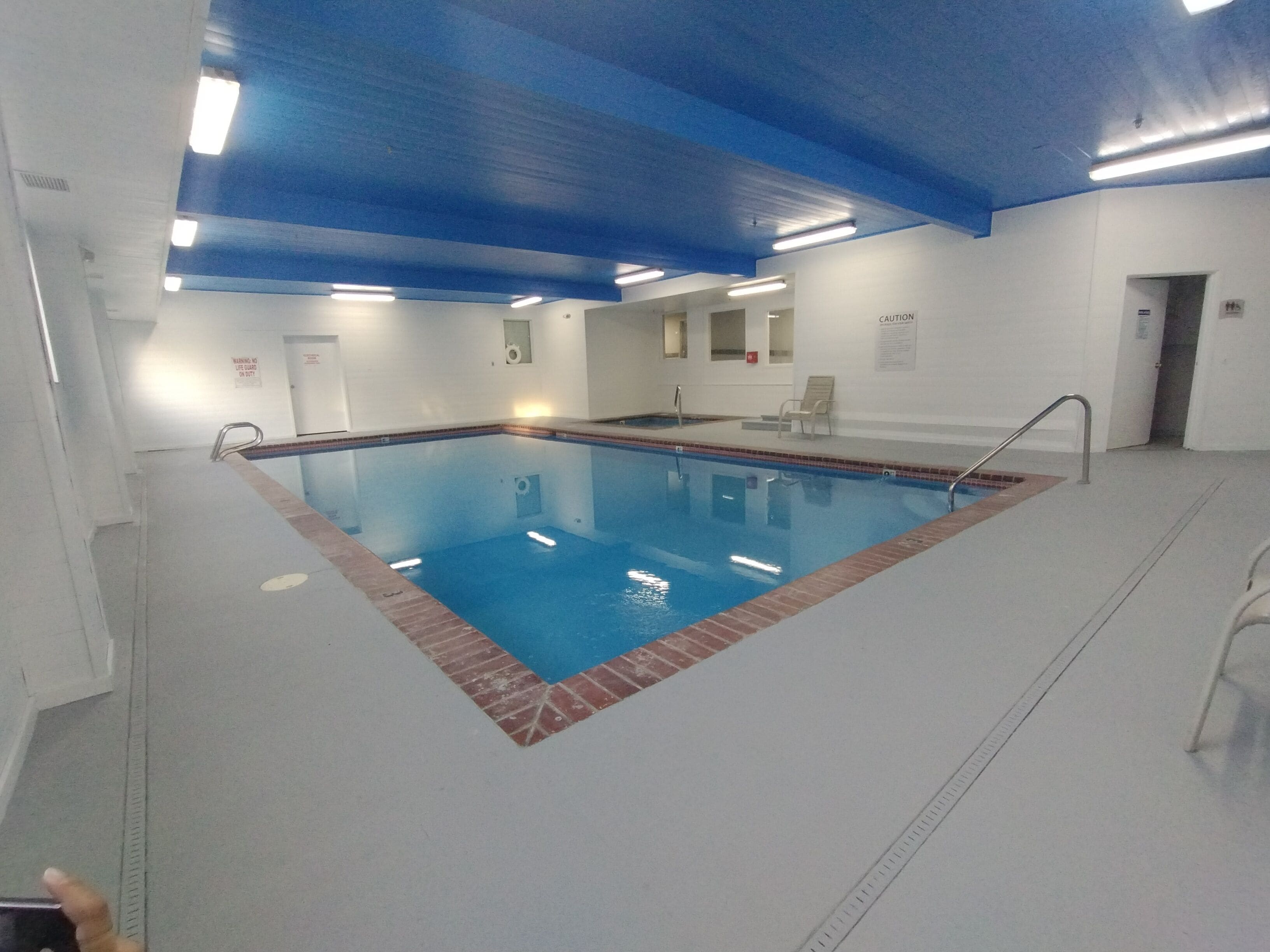 An indoor swimming pool with a blue ceiling and white walls.