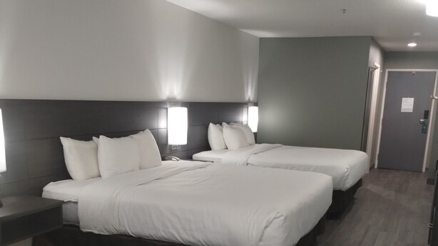Quarto de hotel com duas camas, uma escrivaninha e uma cadeira.