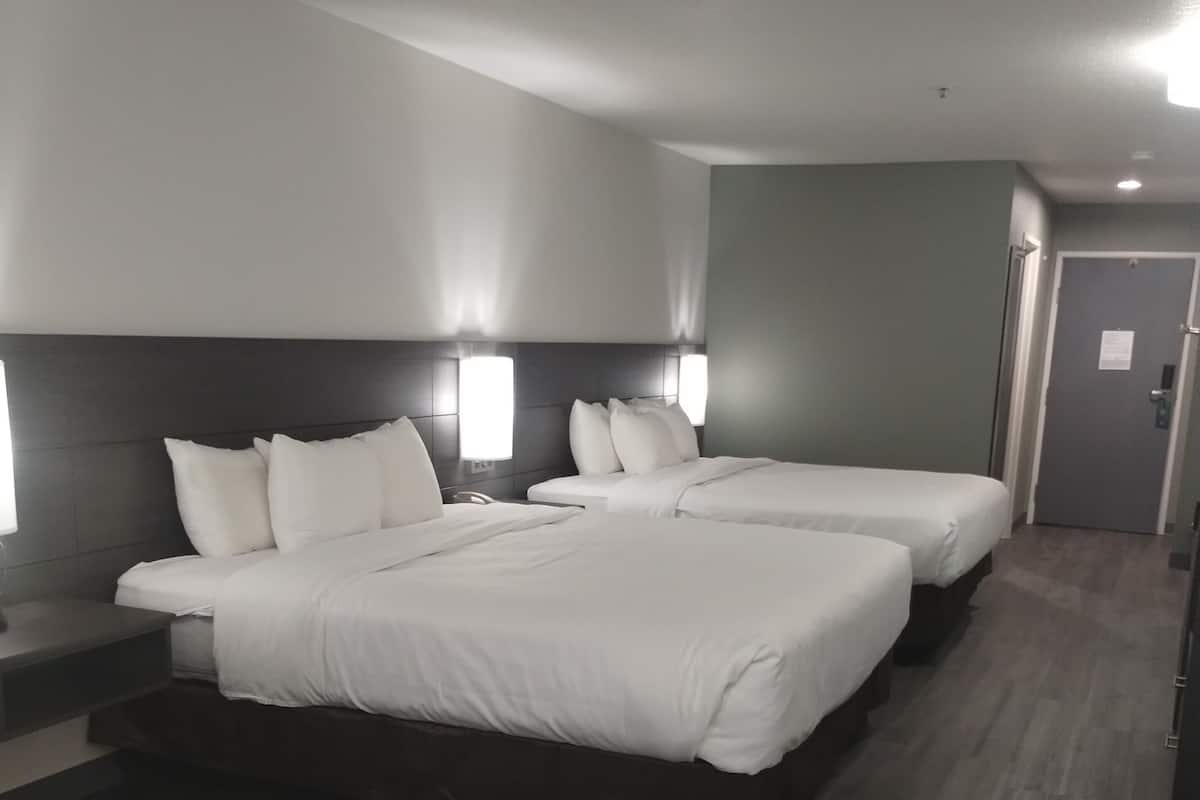 A hotel room with two beds, a desk, and a chair.