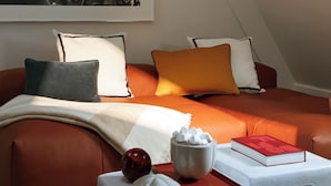 A modern loft bedroom with a cityscape view, a red leather sofa, and a white coffee table with decorative items. - La Villa Saint Germain des Prés (Paris)