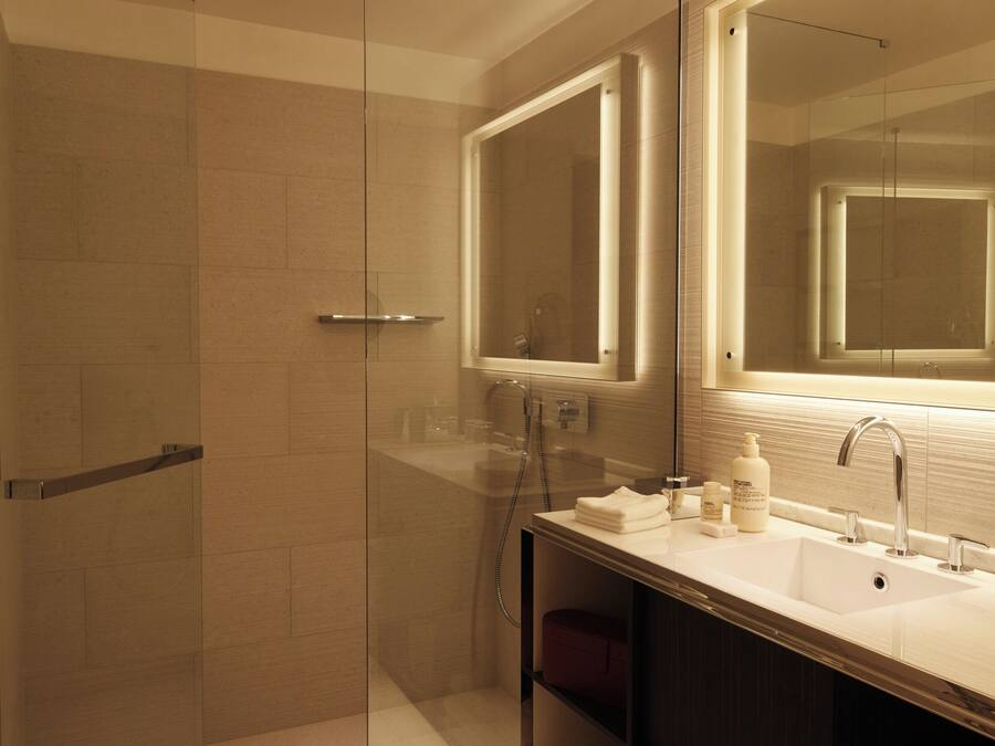 Une salle de bain moderne dotée d’une douche à parois de verre, d’un grand miroir et d’un meuble-lavabo avec un évier et un porte-serviettes.