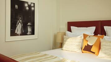 Una camera d'albergo con un letto, un quadro appeso alla parete e un comodino con una lampada.