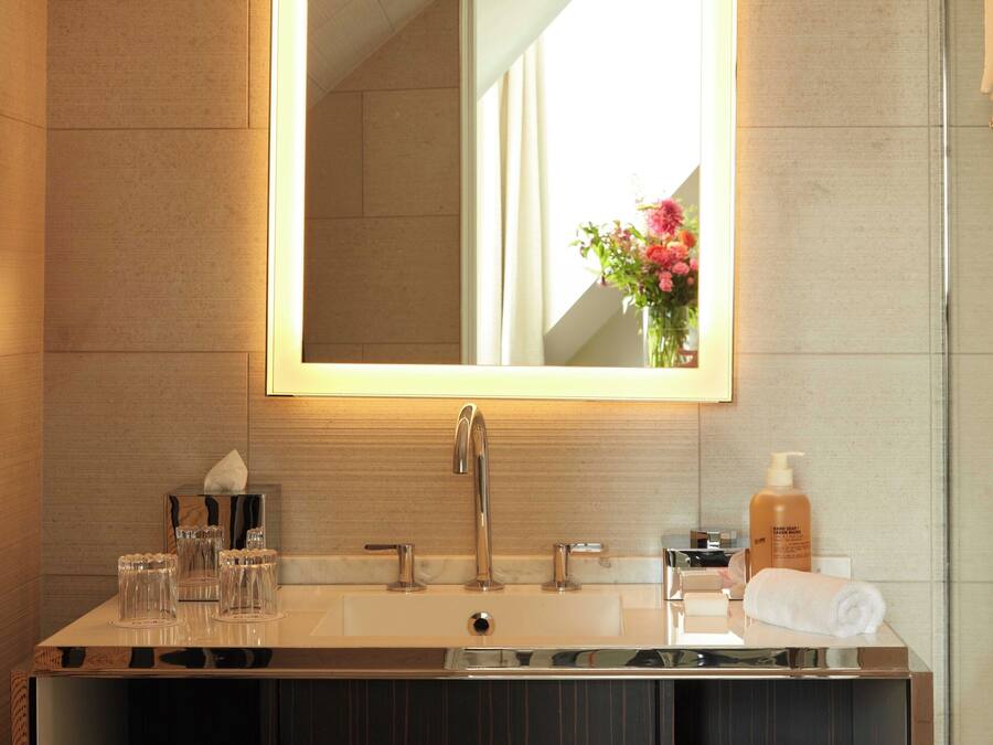 A modern bathroom with a large mirror, a sink, and a vanity with storage.