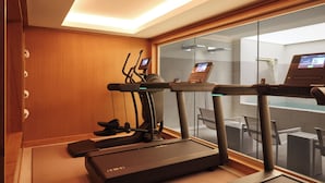 Un gimnasio moderno con cintas de correr, elípticas y una pantalla digital.