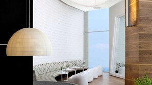 A modern interior with a curved seating area, a large circular light fixture, and a view of the sky through a large window. - Dan Panorama Tel Aviv (Tel Aviv)
