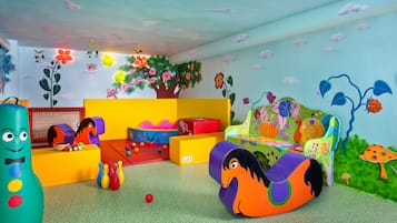 Uma sala de brincar colorida com um sofá, almofadas e uma piscina de bolinhas.