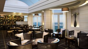 A modern lounge with a high ceiling, seating arrangements, and a view of the ocean. - Dan Panorama Tel Aviv (Tel Aviv)