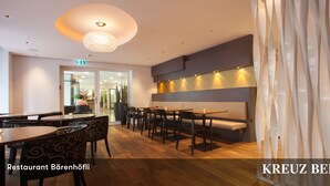 L’intérieur d’un restaurant avec des tables et des chaises en bois, un banc et un lustre moderne.