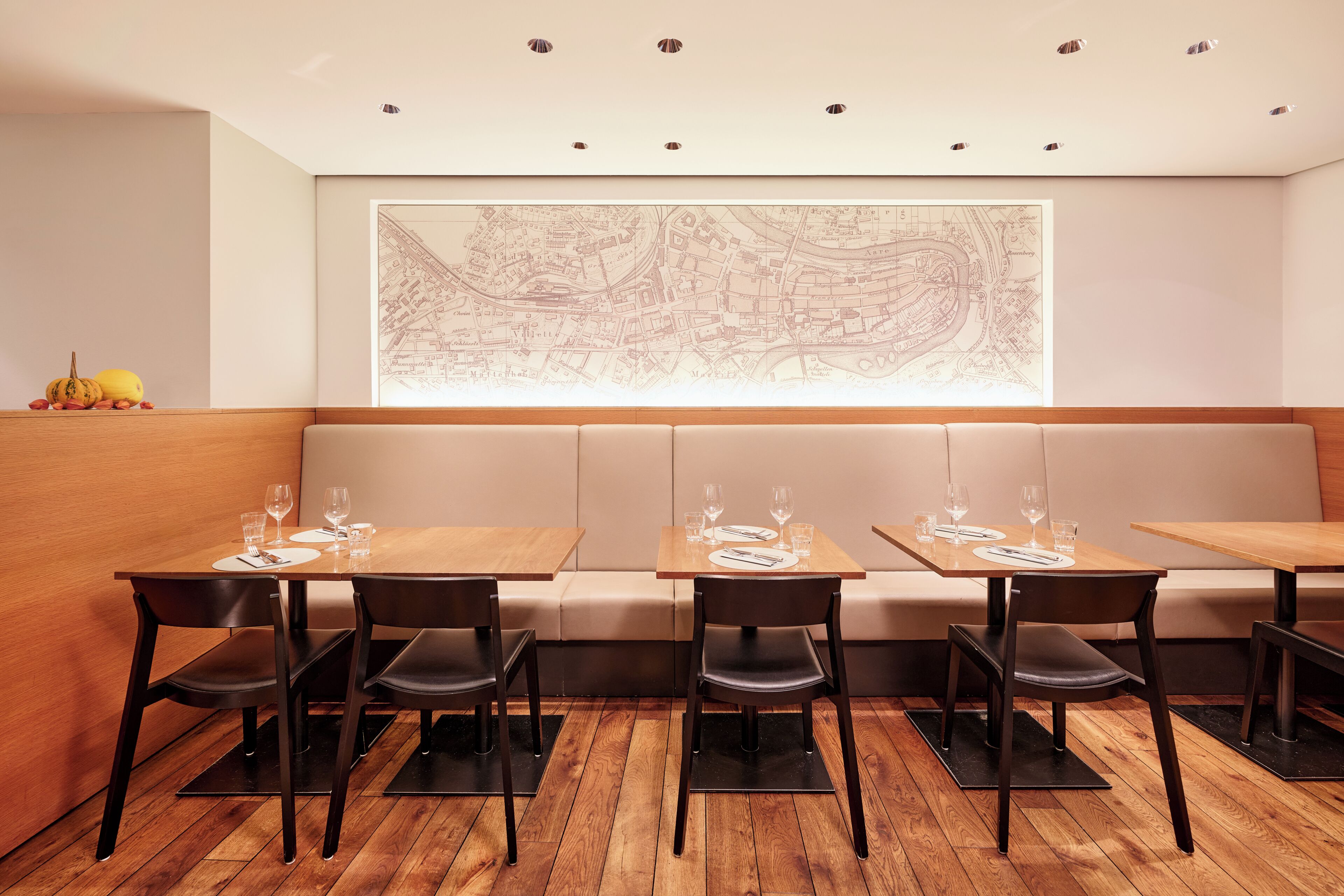 Un restaurante con mesas y sillas de madera, un mapa grande en la pared y suelo de madera.