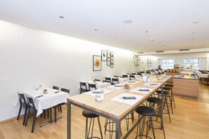 Un'ampia sala da pranzo con diversi tavoli e sedie, un'area bar e opere d'arte appese alle pareti.