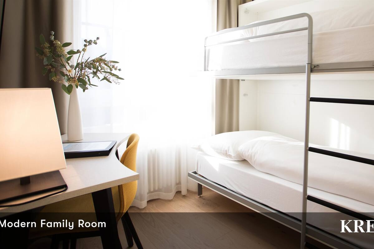 A modern family room with bunk beds, a desk, and a lamp.