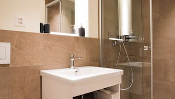 Un baño moderno con ducha acristalada, lavabo blanco y un inodoro.