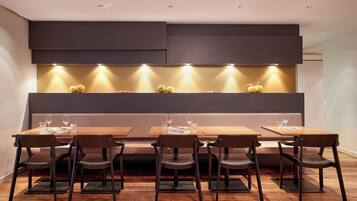 A modern dining area with a long table, six chairs, and a built-in light shelf above.