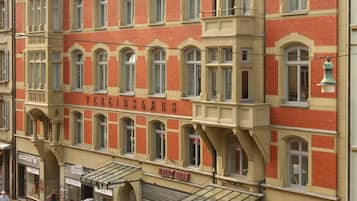 A multi-story building with a red brick facade, multiple windows, and a prominent corner entrance.