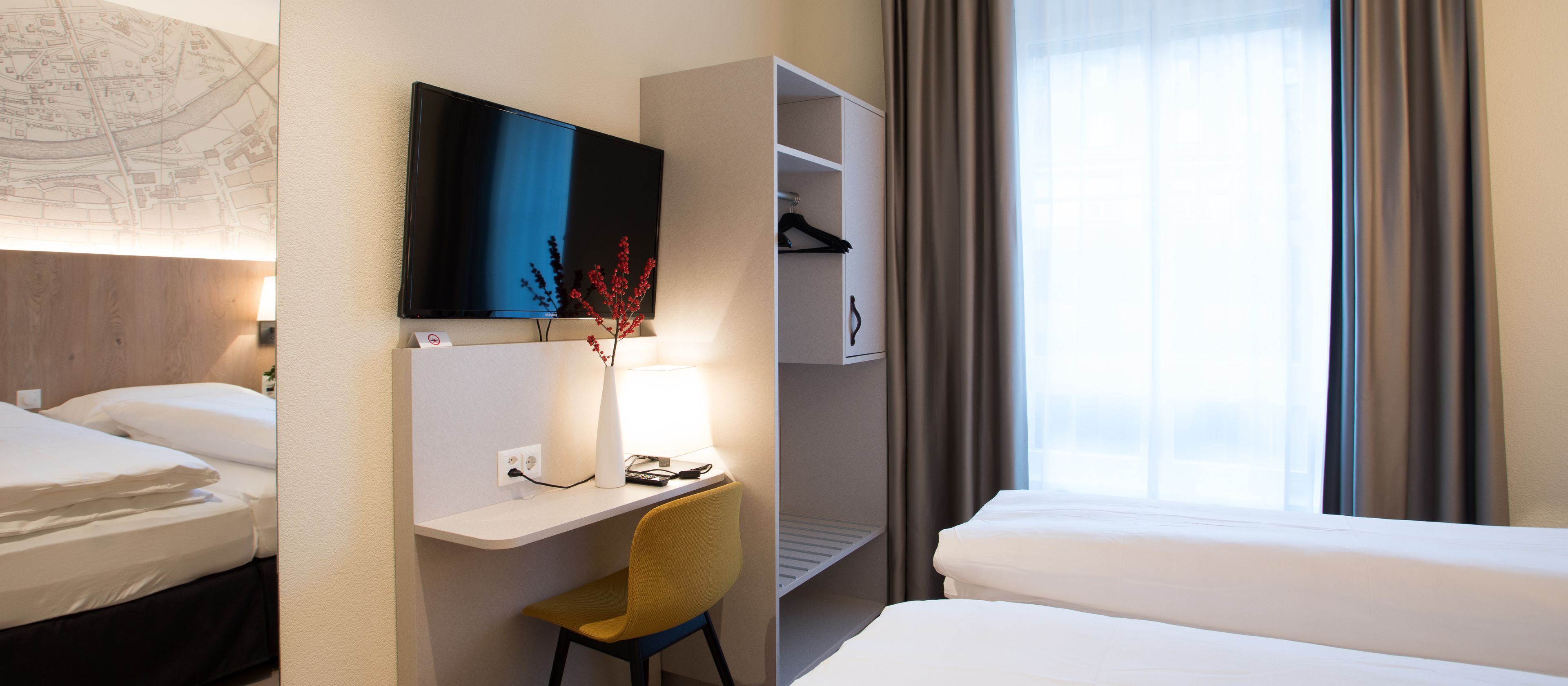 Habitación de hotel con cama, escritorio con silla, televisión y armario.