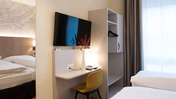 A hotel room with a bed, a desk with a chair, a TV, and a wardrobe.