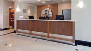 A hotel reception desk with a wooden counter, a digital screen, and a sign that reads "Holiday Inn." - Holiday Inn Palmdale-Lancaster by IHG (Palmdale)