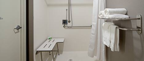A modern bathroom with a shower, a towel rack, and a small table with toiletries.