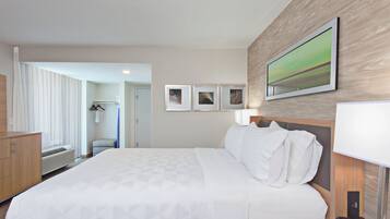 Una habitación de hotel con una cama grande, un escritorio, un teléfono y un cuadro colgado en la pared.