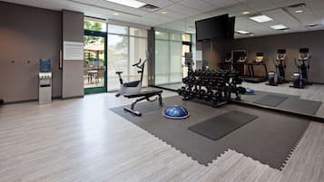 A fitness center with exercise equipment, a water dispenser, and a sign indicating it is closed.