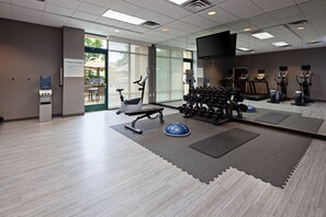 A fitness center with exercise equipment, a water dispenser, and a sign indicating it is closed. - Holiday Inn Palmdale-Lancaster by IHG (Palmdale)