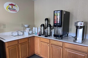 Een kitchenette met een koffieapparaat, een waterdispenser en een wandgemonteerd koffiehoekje.