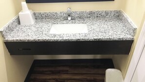 A bathroom with a granite countertop sink, a dark wooden floor, and a white trash bin. - Super 8 by Wyndham Lumberton NC (Lumberton)