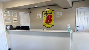 A reception desk with a 'Super 8' sign, a complimentary breakfast sign, and various informational signs. - Super 8 by Wyndham Lumberton NC (Lumberton)
