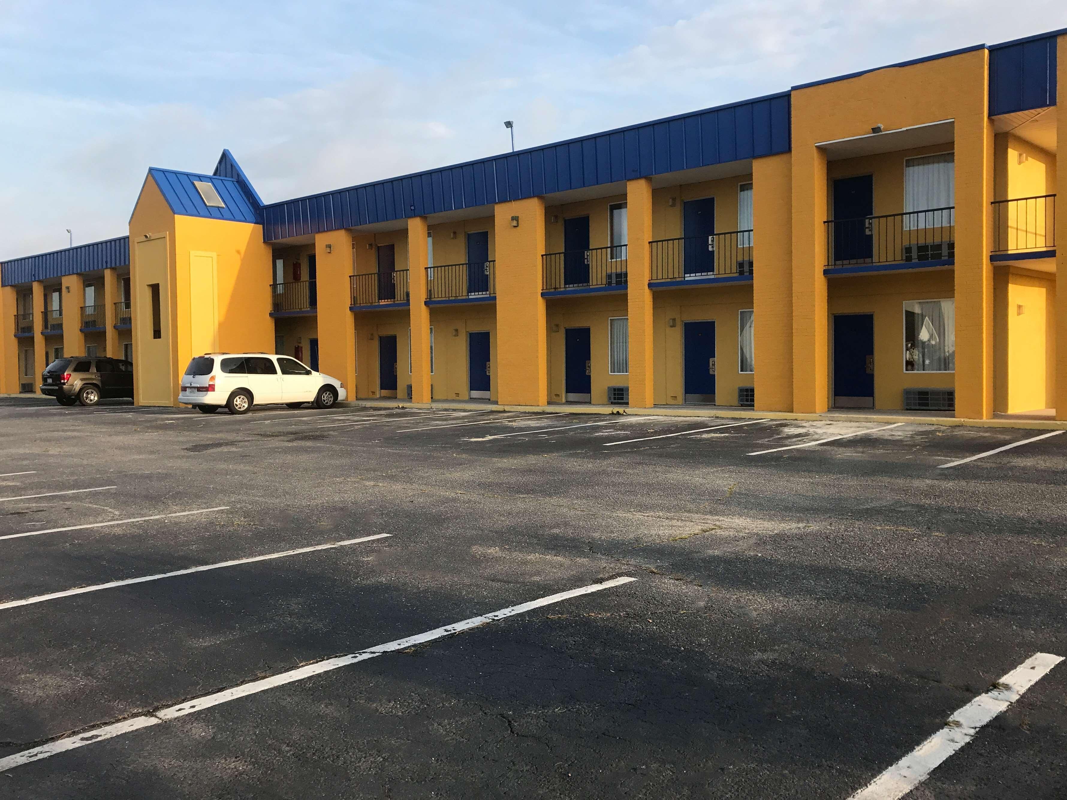 Ein Motel mit mehreren Balkonen, einem Parkplatz und einem blauen Dach.