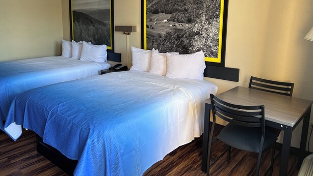 A hotel room with two beds, a desk, and a chair. There are two paintings on the wall. - Super 8 by Wyndham Lumberton NC (Lumberton)