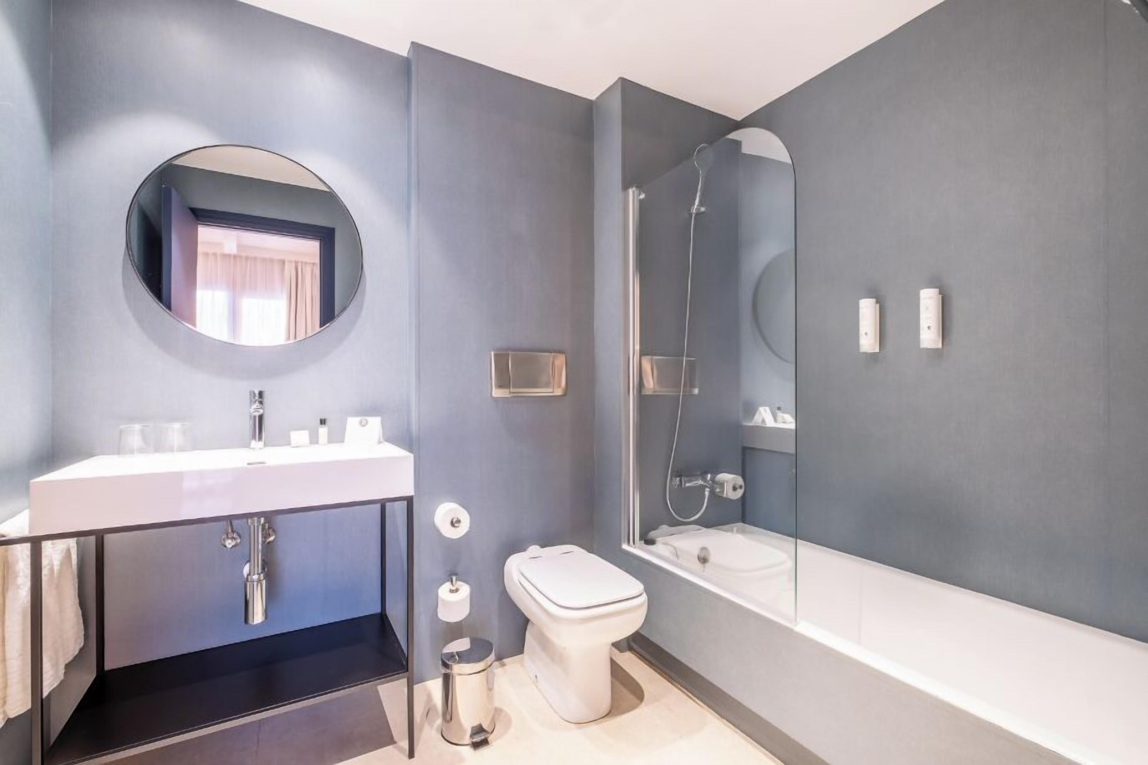 Une salle de bain moderne avec un lavabo blanc, des toilettes et une baignoire.