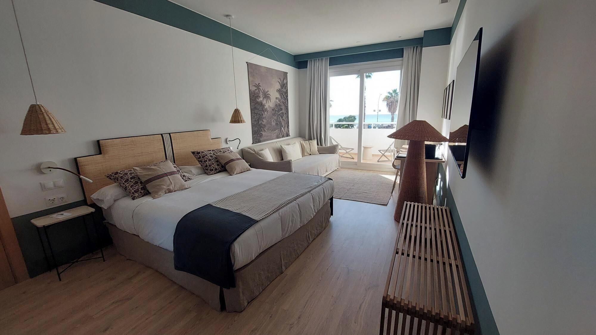 Un dormitorio moderno con una cama grande, un sofá, una mesa de comedor y vistas al exterior.
