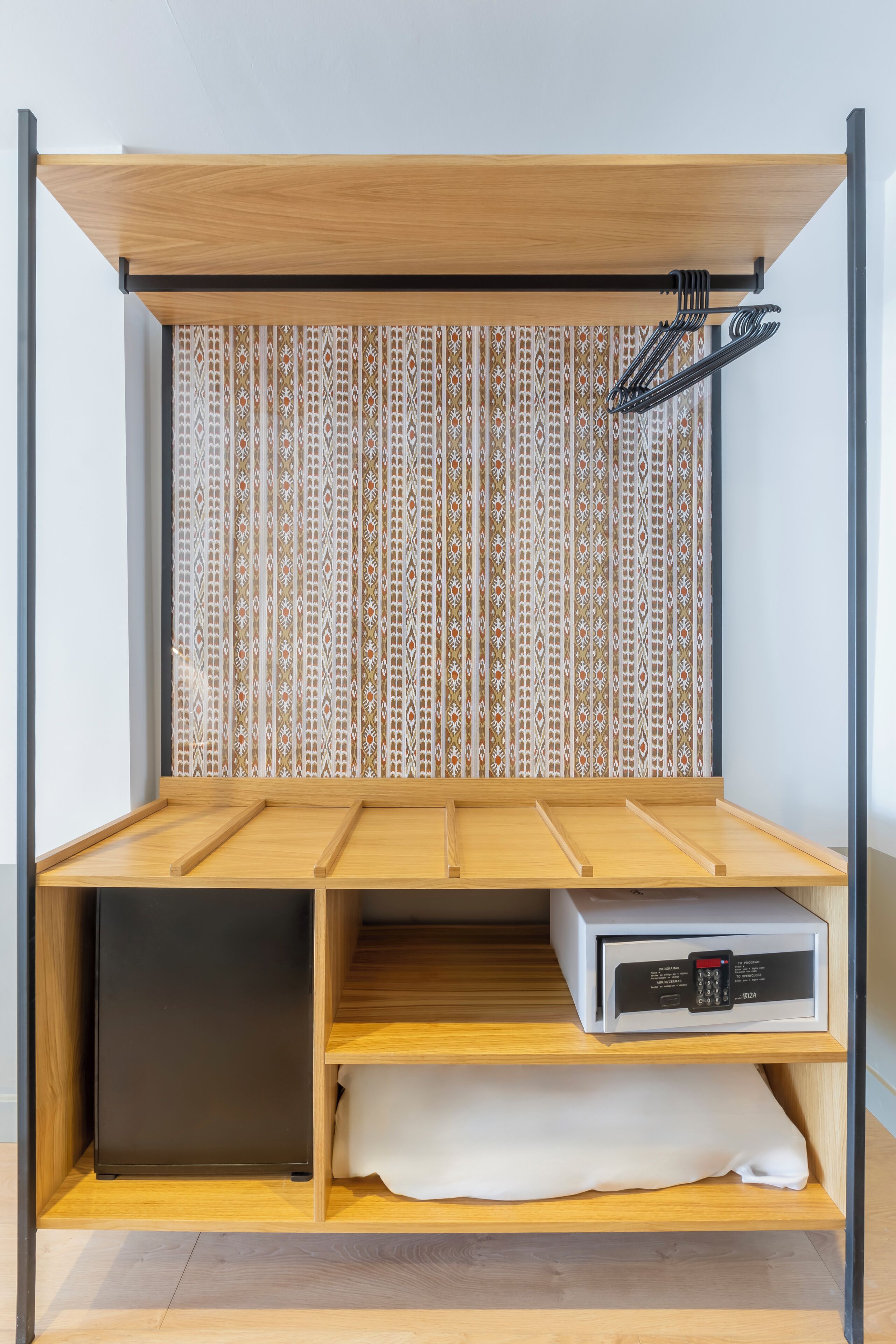 Een compacte kamer met een inbouwkast, een klein bureau en een magnetron.