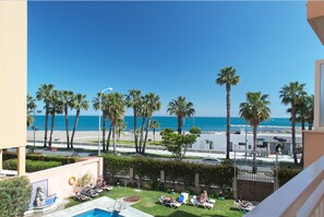 A pool area with lounge chairs and a statue, overlooking a beach with palm trees and the ocean. - Petit Palace Las Vegas formerly known as Soho Boutique Las Vegas (Málaga)