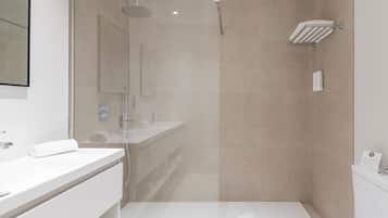 Un baño moderno con ducha envuelta en vidrio, un lavabo blanco y un inodoro.