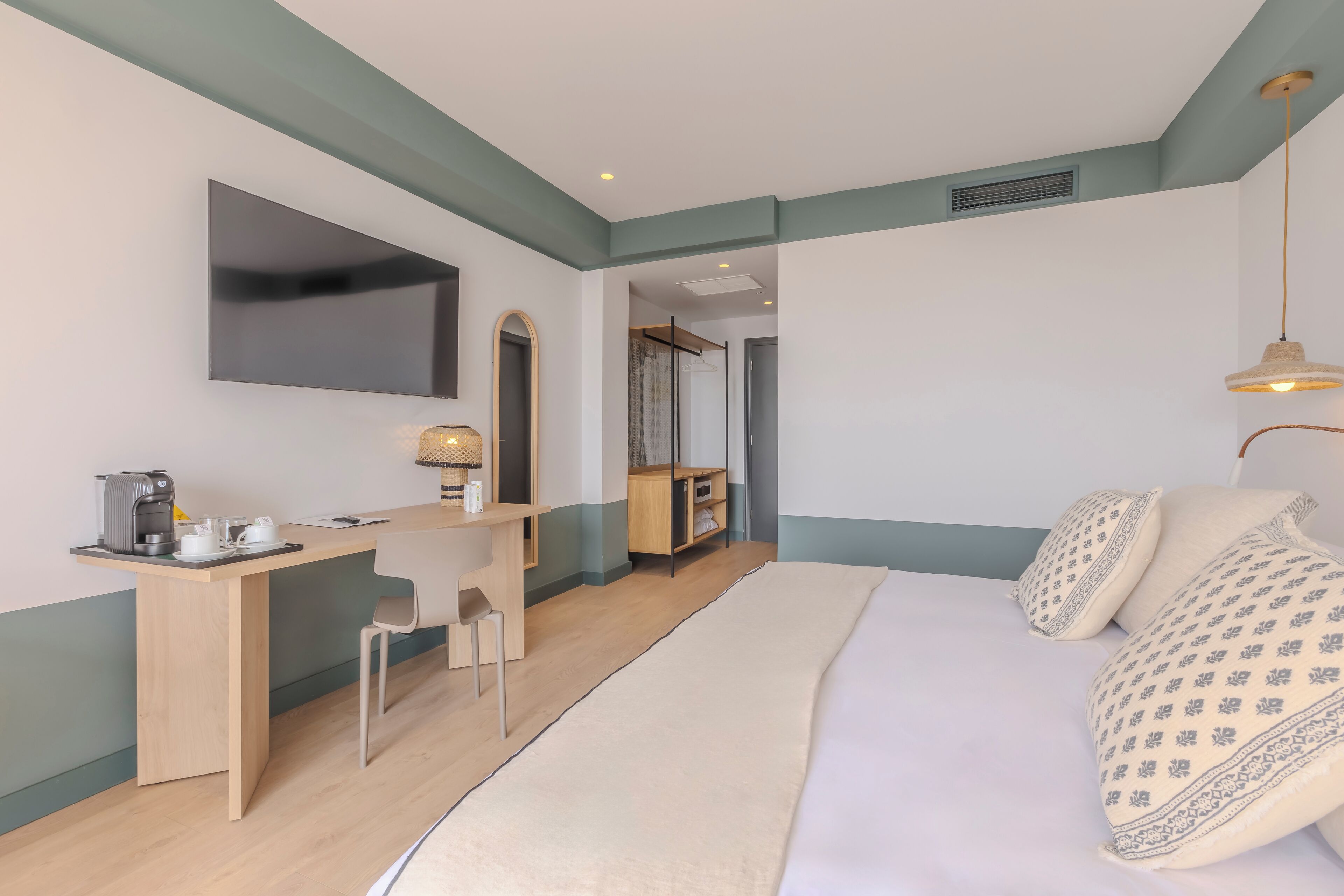 Une chambre d’hôtel avec un lit, un bureau, une chaise, une télévision et une lampe.