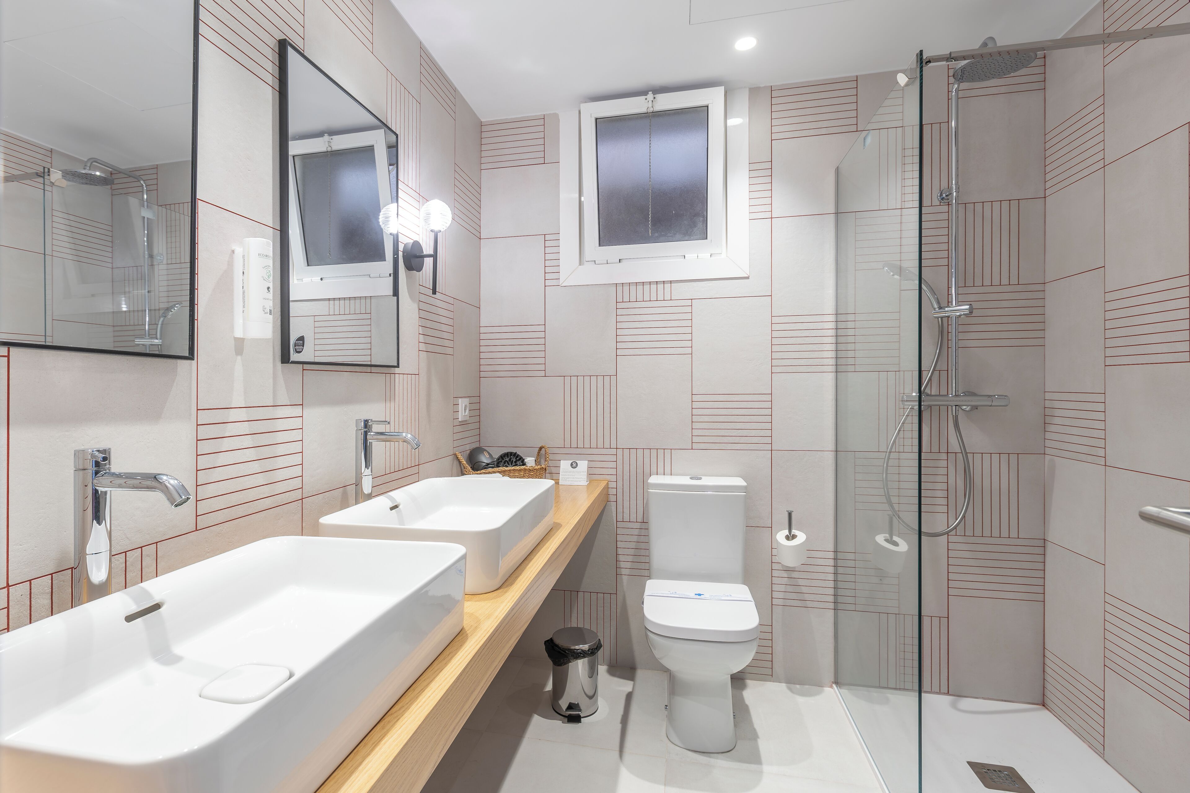 Une salle de bain moderne avec deux lavabos, des toilettes et une douche à parois de verre.